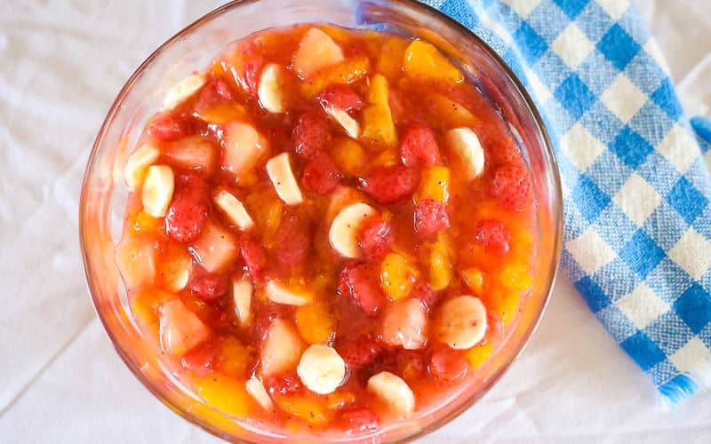 fruit salad with peach pie filling in a glass bowl on table