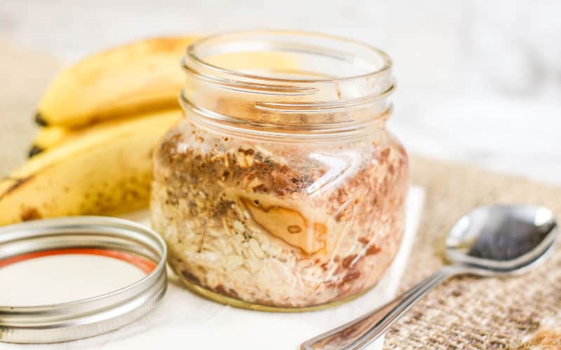banana overnight oats in a jar on the table with bananas