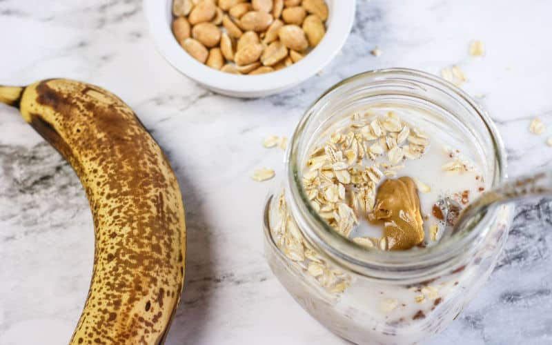 banana on the table with the oats in a jar with a spoon
