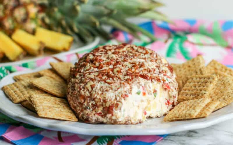 A pineapple cheeseball on the plate with wheat thins