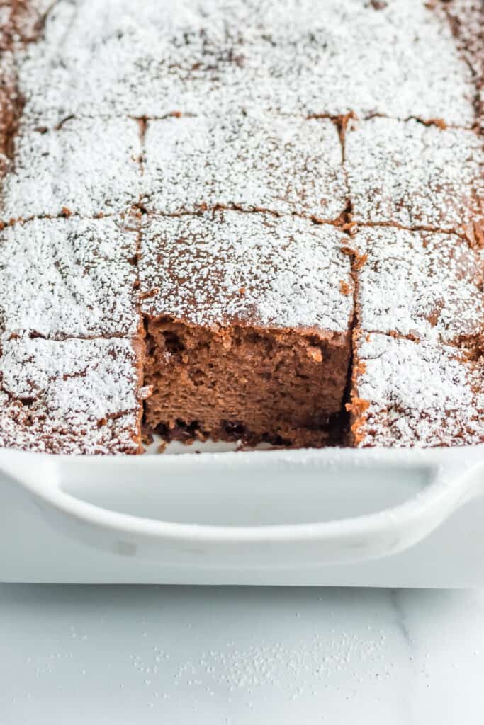 a chocolate chip cake with confectioners sugar in a casserole dish