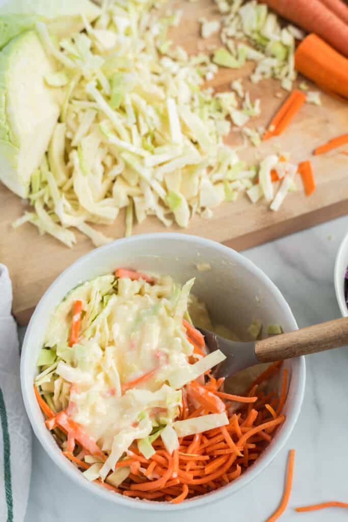 white cabbage and carrots and mayonnaise in bowl with wooden spoon