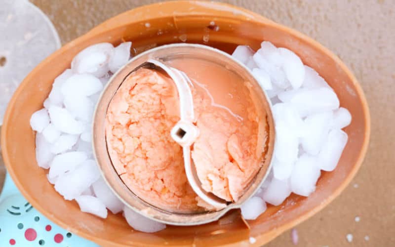 churned orange pineapple ice cream sherbet in ice cream maker with ice