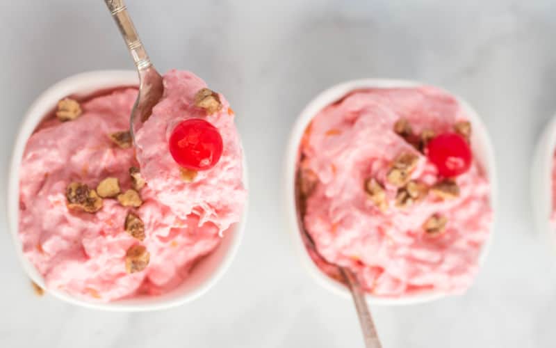 pink salad with cherry on top in a white bowl on table