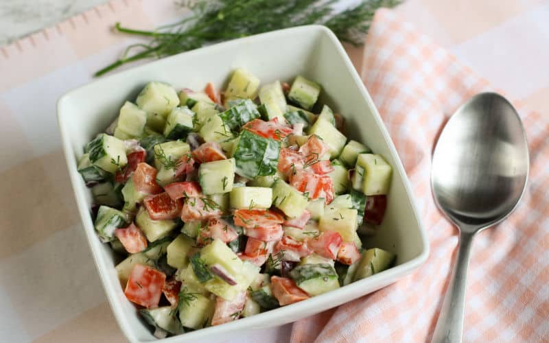 creamy cucumber salad with dill on a table with a spoon