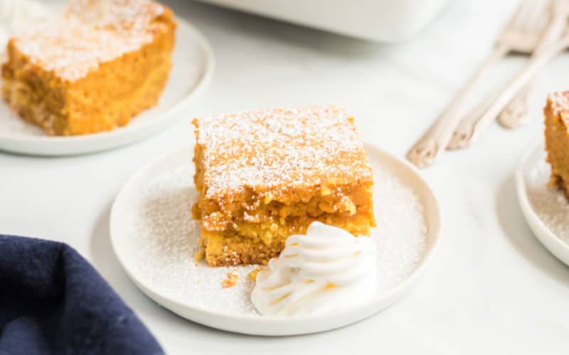 gooey pumpkin pie cake with confectioners sugar on a white plate