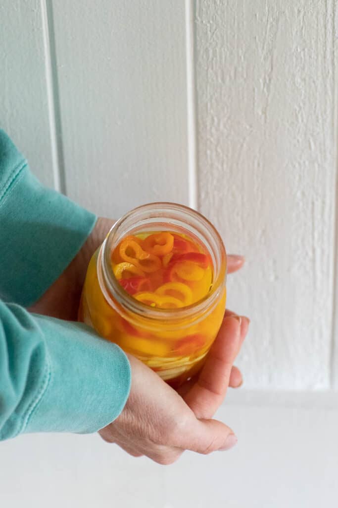 person holding jar of pickled sweet peppers