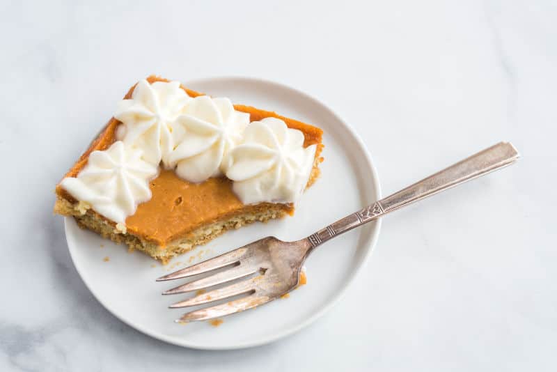 slice of sweet potato slab pie with whip cream on a table with fork