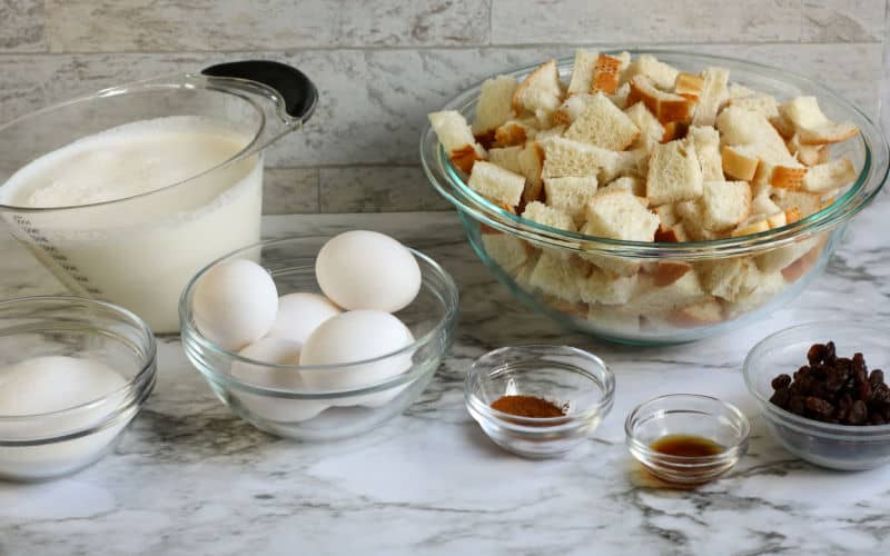 ingredients for bread pudding ont able, bread raisins cinnamon milk eggs sugar