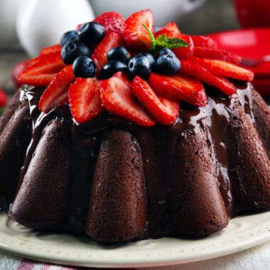 chocolate cake iced with chocolate ganache topped with strawberries and blueberries