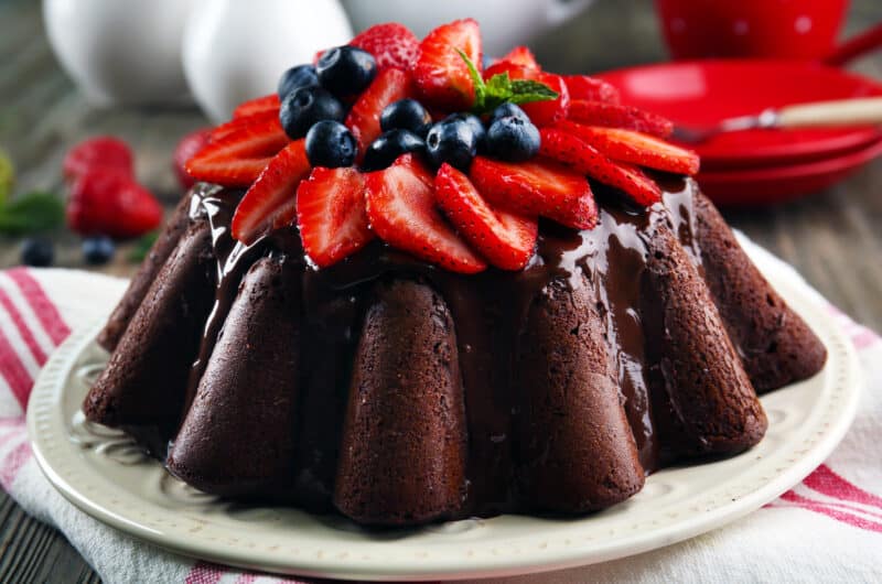 chocolate cake iced with chocolate ganache topped with strawberries and blueberries